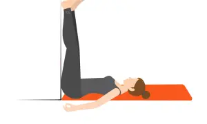 En kvinna stretchar rygg efter gym genom att ligga på en matta med benen uppåt mot en vägg.