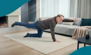 Äldre man gör en övning på alla fyra för att avlasta ryggen. Han sträcker ut ett ben och en arm för balans.