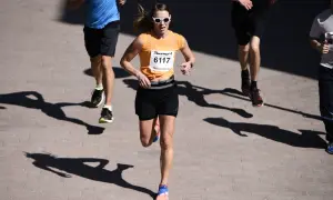 En kvinna i orange tröja och solglasögon springer i ett lopp. Hon är nummer 6117. Hur lång tid tar det att springa 5 km?