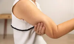 En person håller om sin arm, där man kan se tydliga muskler i armen.