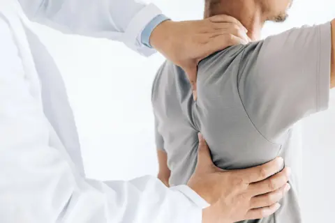 Läkare undersöker en patient med ont skulderblad som begränsar andas.