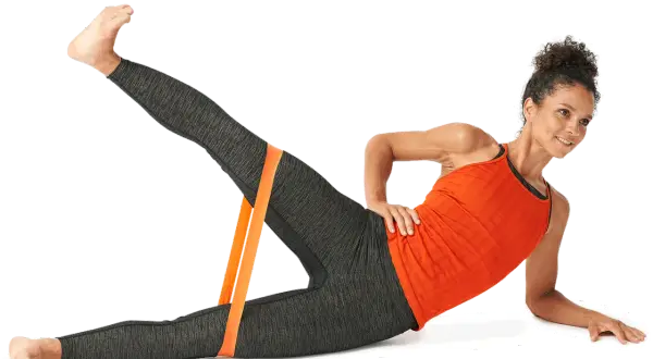 Kvinna utför sidoliggande benlyft med ett orange träningsband runt anklarna för att stärka höften.