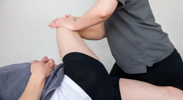 Fysioterapeut behandlar en person med ont i lårmuskeln genom att sträcka ut benet.