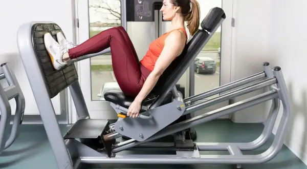 Kvinna tränar benpress rumpa på gym.