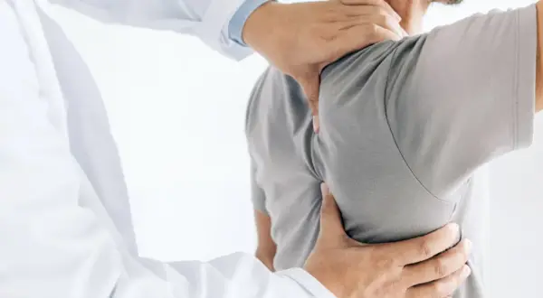Läkare undersöker en patient med ont skulderblad som begränsar andas.
