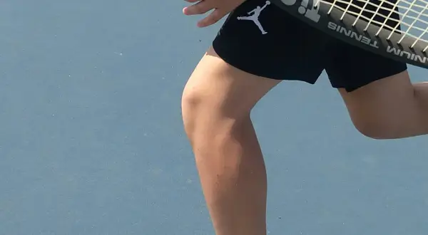 Tennisspelare med ont i ljumsken tips. En person i svarta shorts med Jumpman-logga på en blå tennisbana.