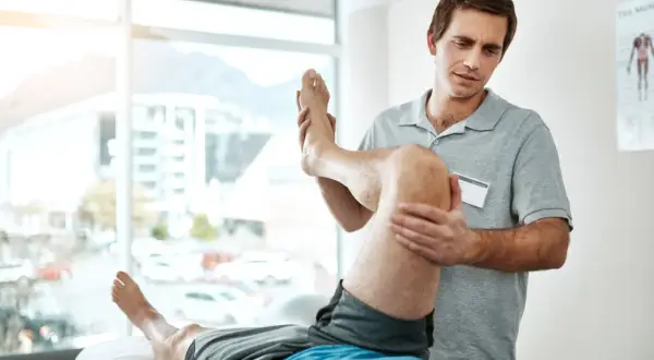 Fysioterapeut undersöker en patients vadmuskel, möjligen för att identifiera triggerpunkter vaden.