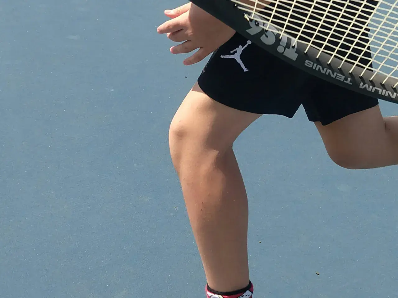 Tennisspelare med ont i ljumsken tips. En person i svarta shorts med Jumpman-logga på en blå tennisbana.