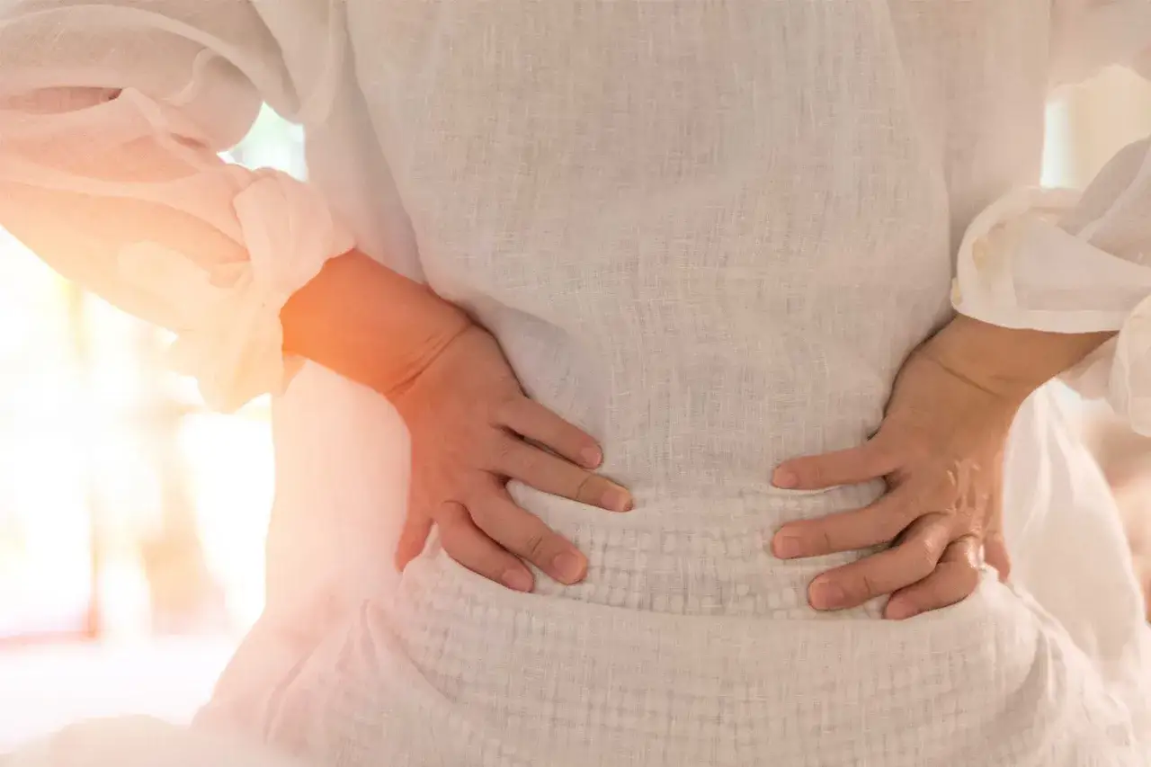 Gravid kvinna med h&auml;nderna p&aring; ryggen, som visar ont i leder.