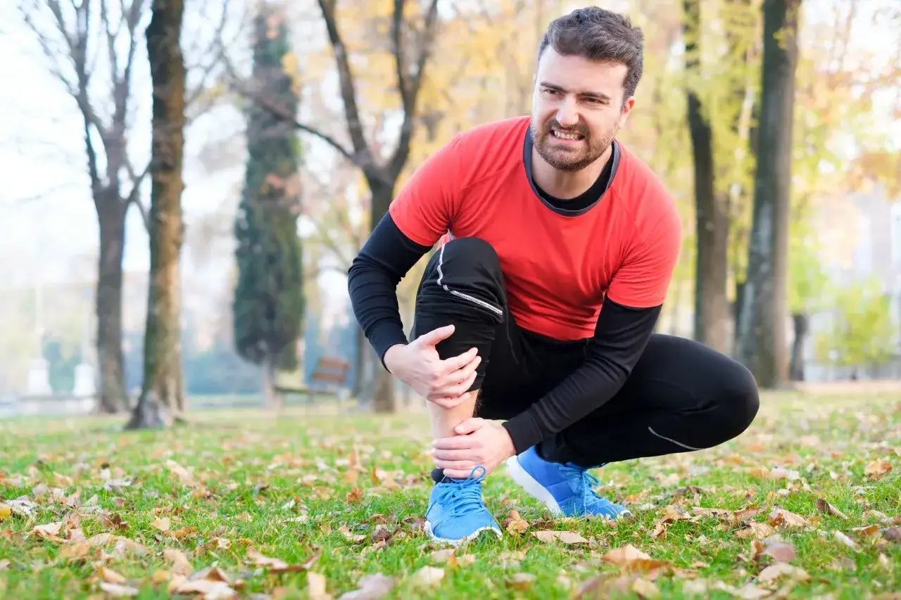 Man med sm&auml;rta i vaden, kanske beh&ouml;ver stretcha smalbenen efter l&ouml;prundan i parken.