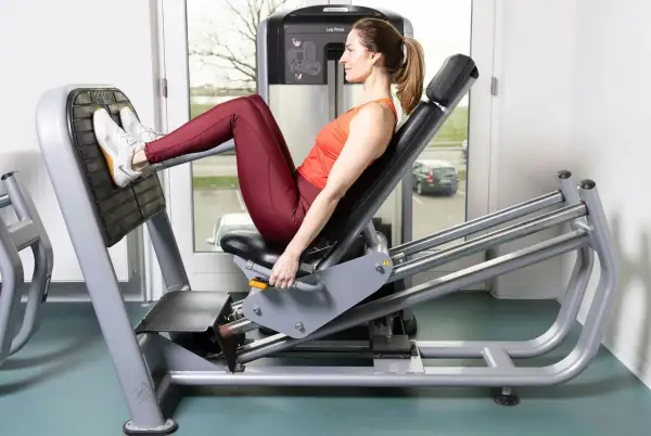 Kvinna tränar benpress rumpa på gym.