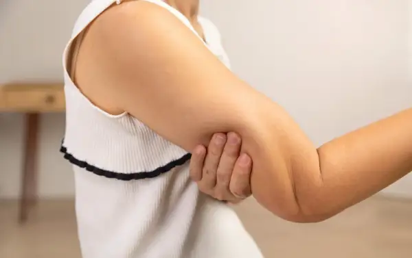 En person håller om sin arm, där man kan se tydliga muskler i armen.