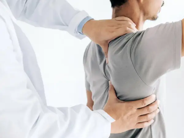 Läkare undersöker en patient med ont skulderblad som begränsar andas.